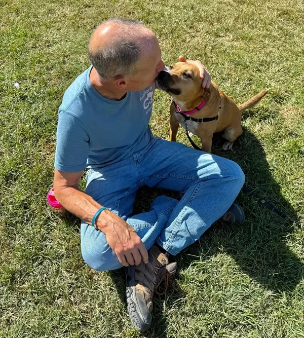 Volunteer and dog, sitting in the grass