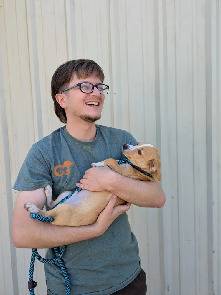 Smiling young man holding a puppy in his arms